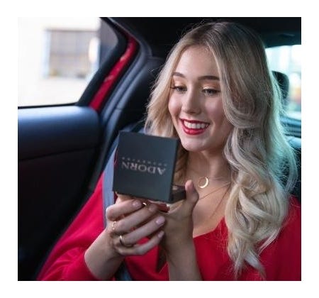 Young female applying a red lipstick in the back seat of a car